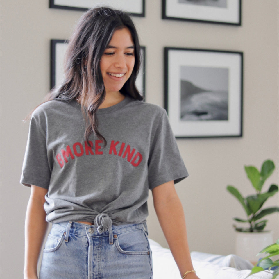 Ali wearing the unisex Bmore Kind t-shirt in our apartment near a plant.